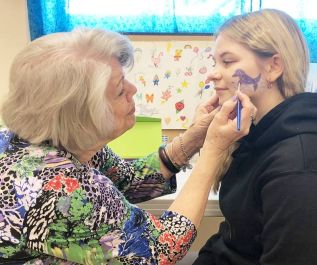 Volunteer Linda Ritchie and her granddaughter Charlize brushing up on face painting skills.